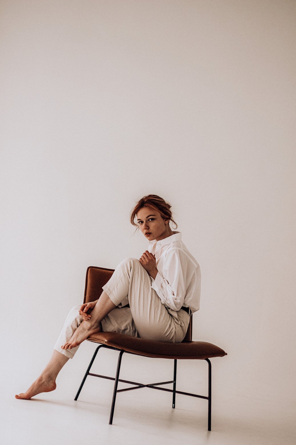 Stylish woman sitting on chair in studio